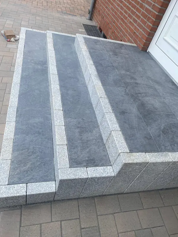 Eingangstreppe aus Granit-Blockstufen mit dunklen Plattenauflagen