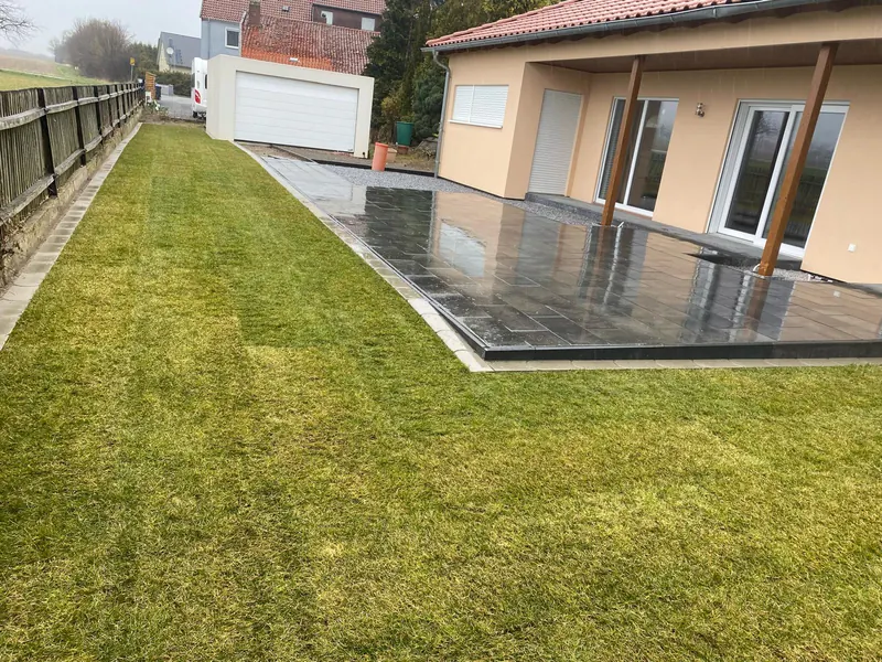 Frisch verlegter Rollrasen neben einer Terrasse aus großformatigen Platten