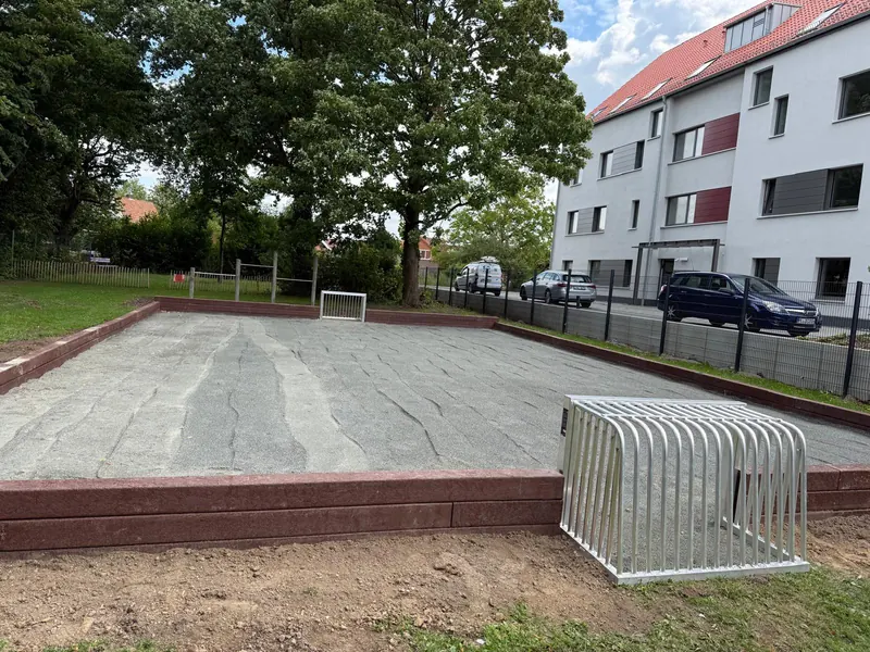Neu angelegte Spielfläche mit Einfassung und Fahrradständer an einer Wohnanlage