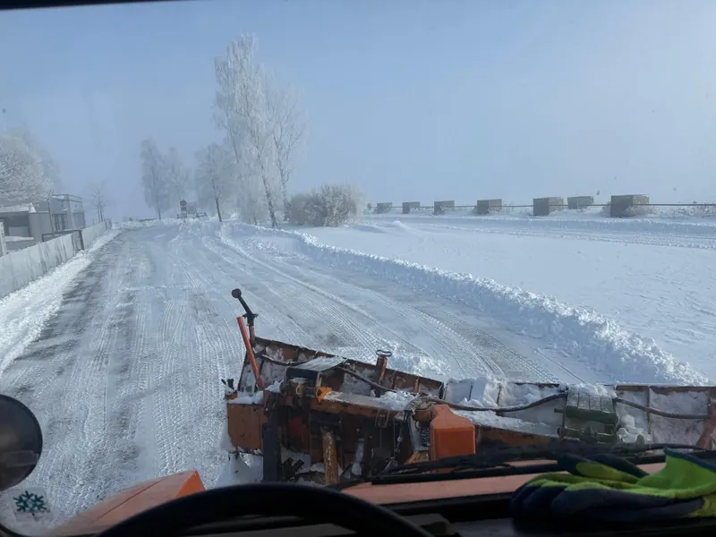 Blick aus dem Räumfahrzeug mit Schneeschild auf eine verschneite Straße